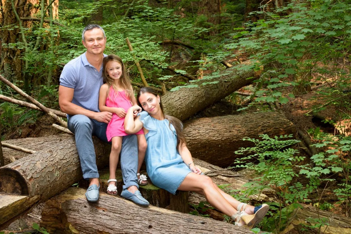 A family sitting together on a fallen log in a Langley forest during a golden-hour session