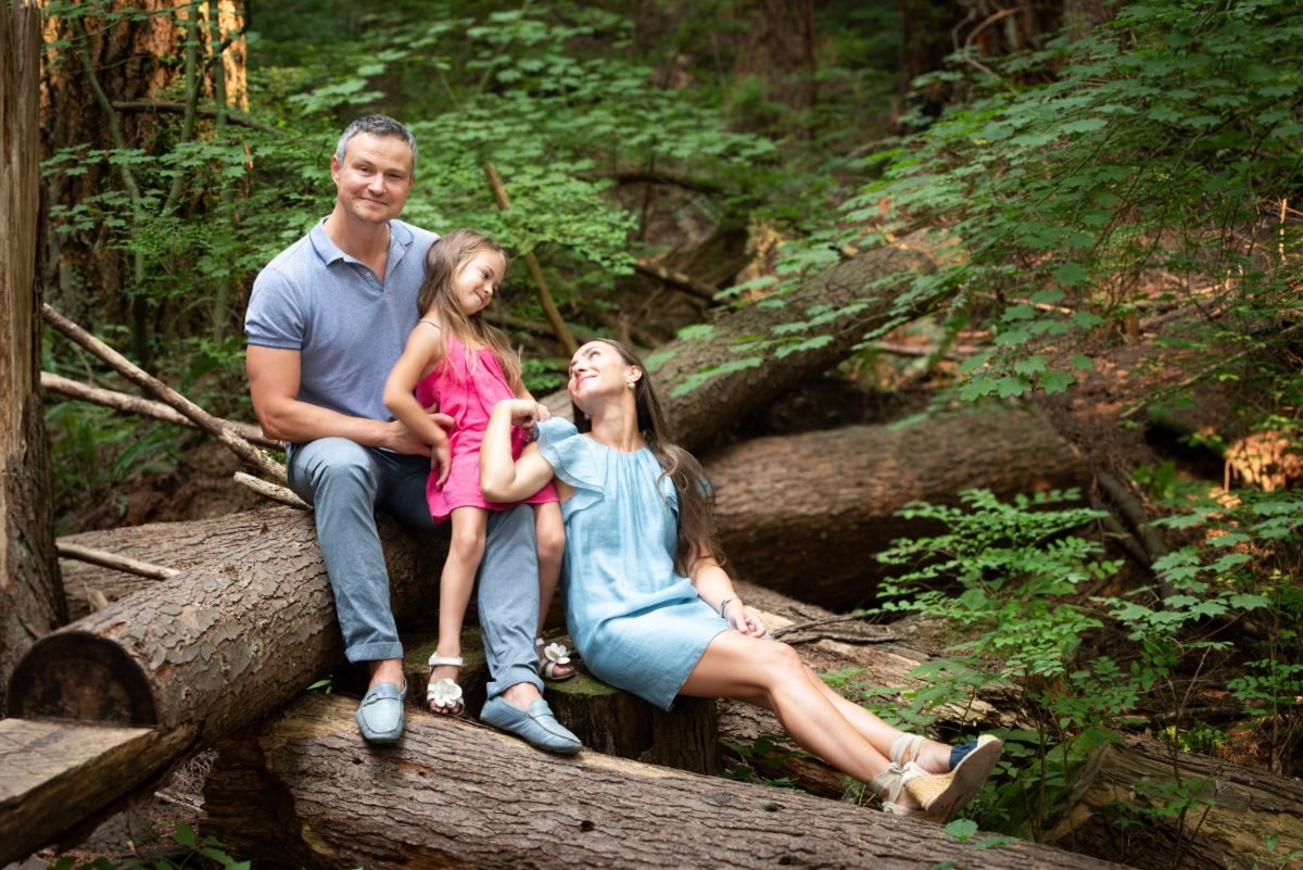 Mother, father and their daughter photographed together on a fallen log in a Langley forest