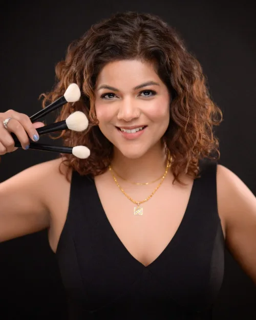 Personal branding portrait of a makeup artist holding her brushes on a dark backdrop