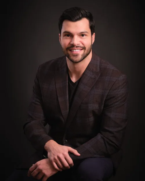 Personal branding portrait of Murilo Tavares in a textured jacket on a dark backdrop