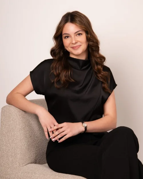 Seated personal branding portrait of a woman in black against a warm backdrop