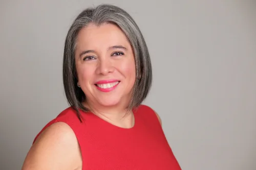 Professional headshot of a woman in a red dress on a grey studio backdrop