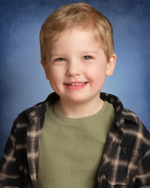 A boy in a plaid shirt on a classic mottled blue backdrop