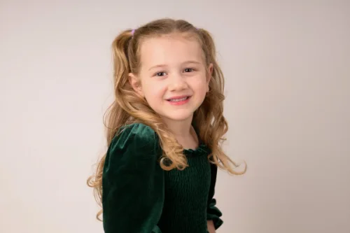 A girl in a green velvet dress glancing back over her shoulder