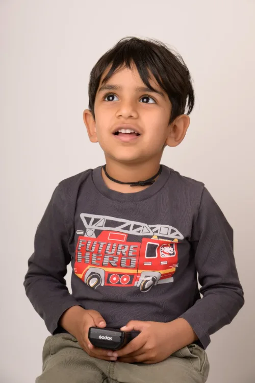 A boy in a fire-truck shirt holding a toy
