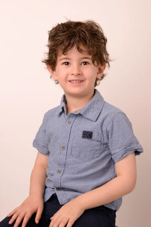 A boy with curly hair in a blue polo shirt