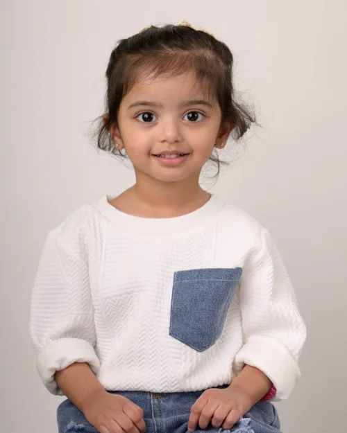 A girl in a white sweater with a denim pocket detail