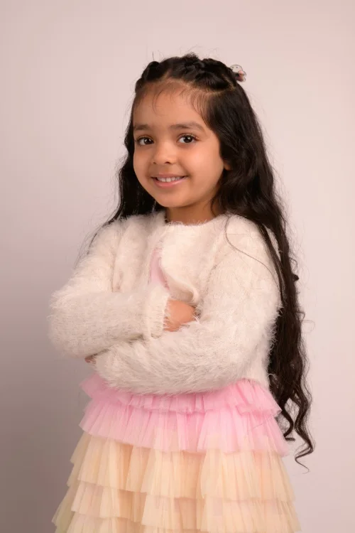 A girl in a white fluffy cardigan with her arms crossed