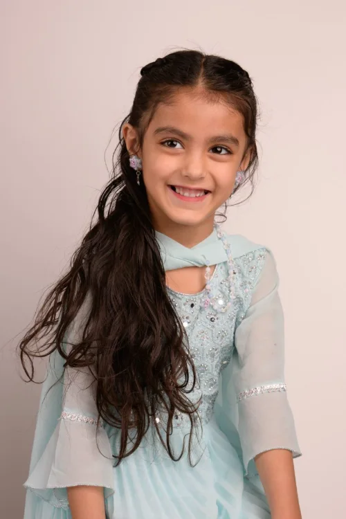 A girl with long dark hair in a teal beaded dress