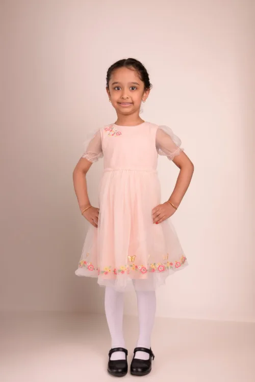 A girl in a blush tulle dress with her hands on her hips