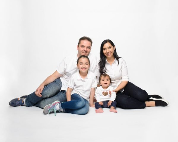 Family sitting on the grass under a flowering shrub at an outdoor session in the Fraser Valley