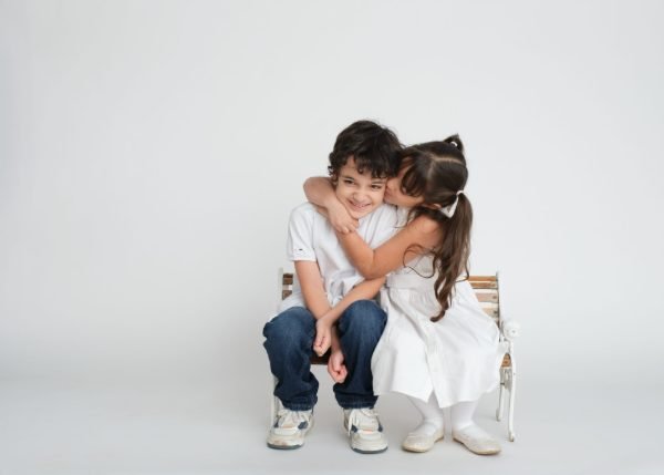 Two young siblings hugging on a studio bench during a family session in Langley