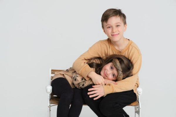 Brother and sister on a studio bench during a family portrait session in Langley