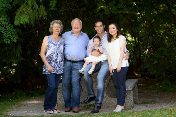 Parents and their toddler on a bench framed by blue hydrangeas at an outdoor family session