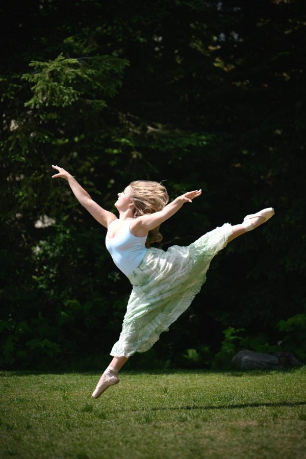 Graduating ballet dancer mid-leap on the lawn during a Langley grad session