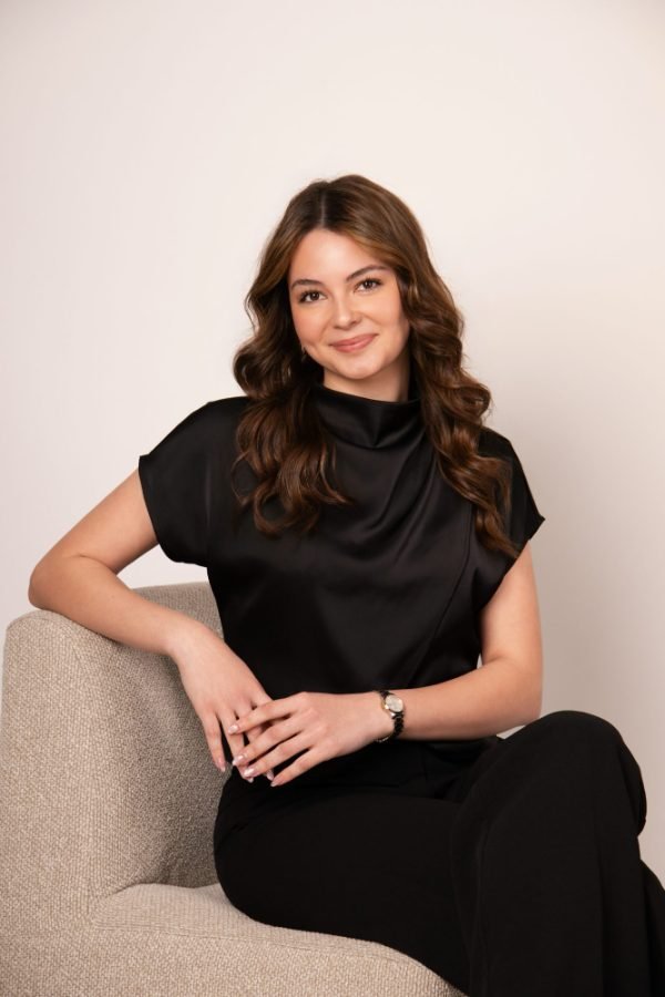 Grad portrait of a graduate in a black satin top seated in the Langley studio
