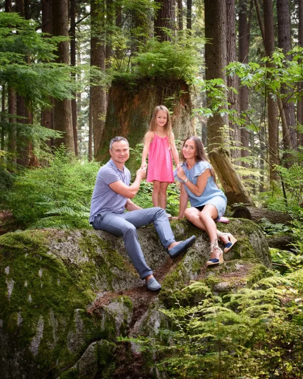 Parents and their daughter on a mossy boulder in an old growth forest during an outdoor family session