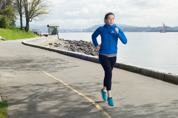 Athletic apparel campaign photography of a runner in a blue technical jacket on the Vancouver seawall