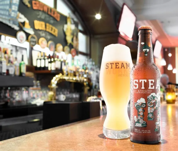 Brewery photography of a craft IPA bottle and full glass on the brass bar of a Vancouver brewpub