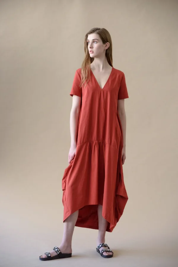 E-commerce clothing photography of a model in a rust cotton midi dress against a neutral studio background