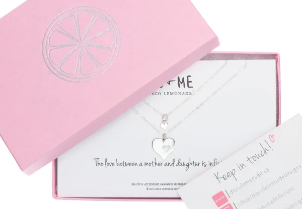 Packaging photography of a mother and daughter necklace set in a pink gift box with a card