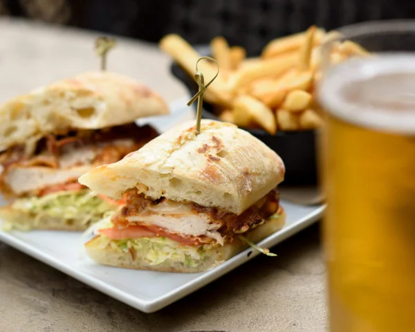 Pub menu photography of a chicken ciabatta sandwich with fries and a cold draught beer