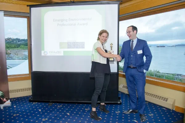 Presenter shaking hands with an award recipient on stage at an environmental industry awards banquet