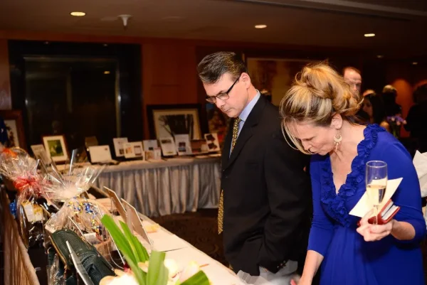 Two guests browsing the silent auction table at a charity fundraising gala