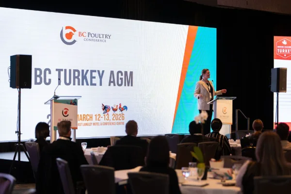 Wide view of the main stage and delegate tables at an annual general meeting in the Fraser Valley
