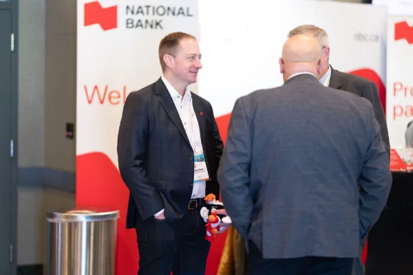 Two delegates talking in front of a sponsor branded wall at a conference reception
