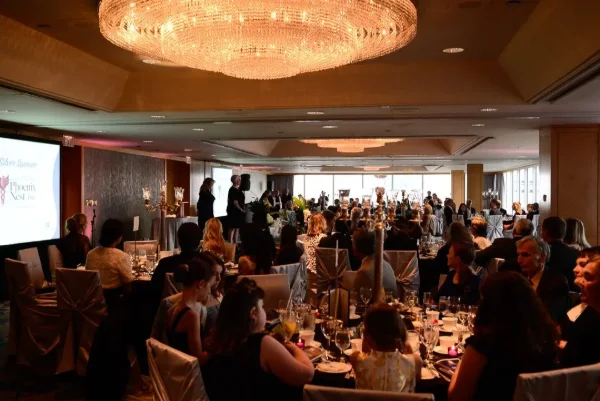 Guests seated at banquet tables during a charity fundraising gala dinner overlooking the Vancouver waterfront