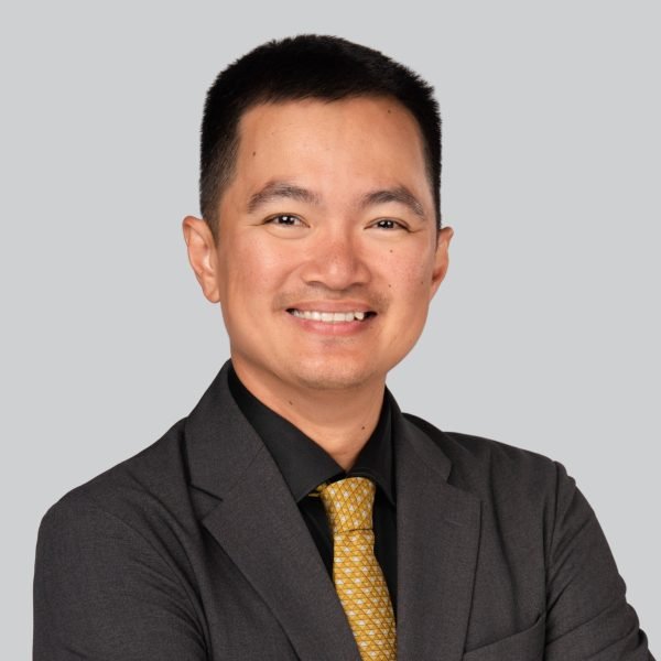 Conference headshot of a man in a dark blazer and yellow patterned tie