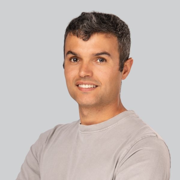 Conference headshot of a man in a grey crewneck sweater photographed at an event booth