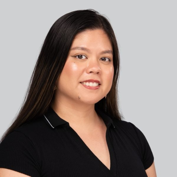 Conference headshot of a woman with long dark hair in a black polo shirt