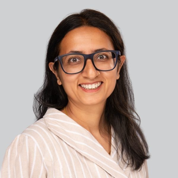 Conference headshot of a woman in glasses wearing a cream shawl