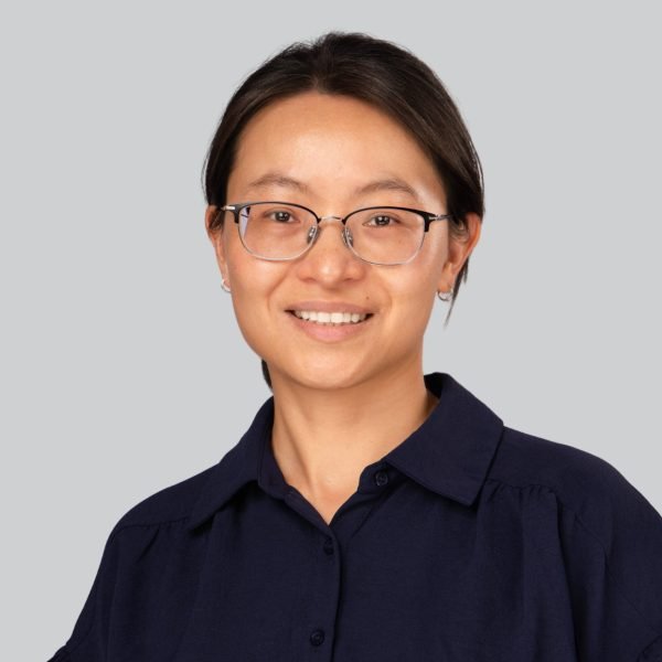 Conference headshot of a woman in glasses and a navy top at a headshot booth