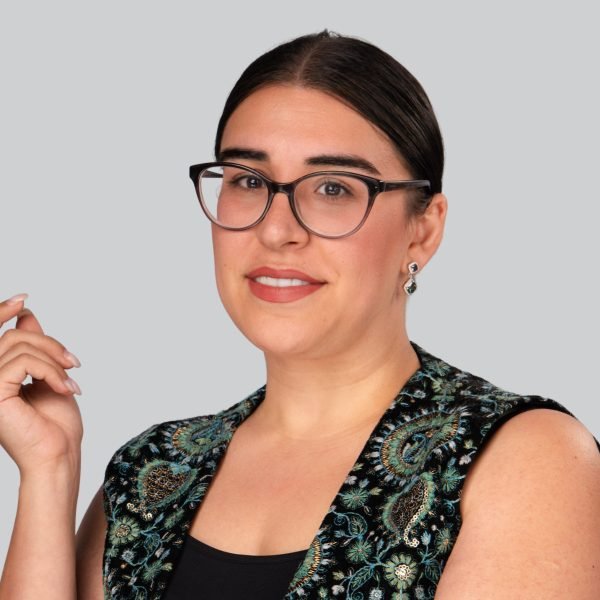 Conference headshot of a woman in glasses wearing a patterned top at an event headshot booth