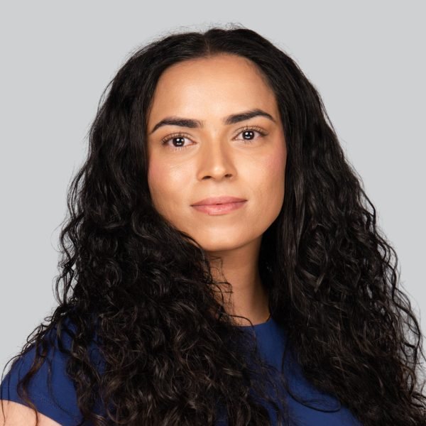 Conference headshot of a woman with long curly hair in a navy top