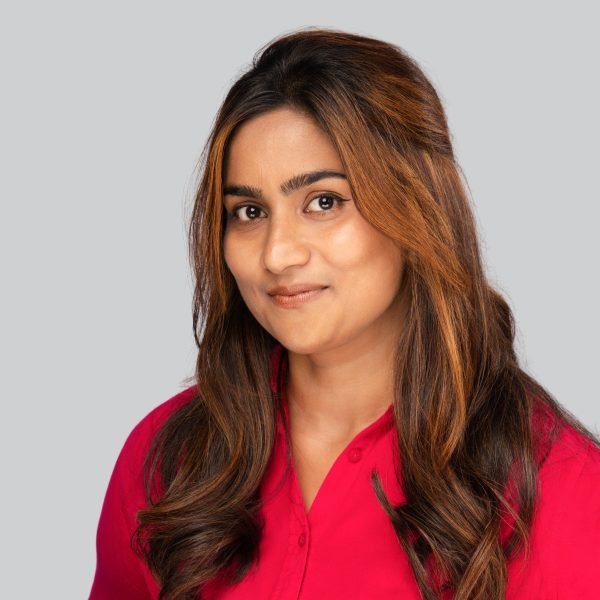 Conference headshot of a woman in a red blouse on a grey studio backdrop