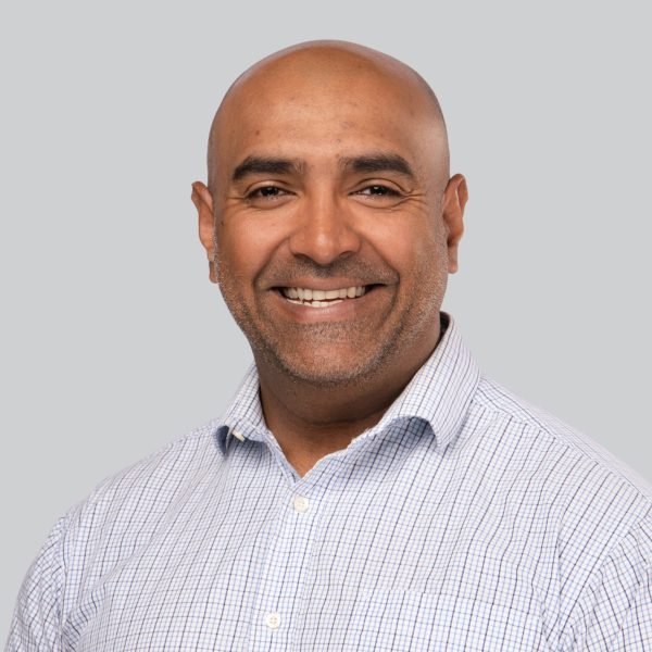 Event headshot booth portrait of a smiling man in a light blue patterned shirt