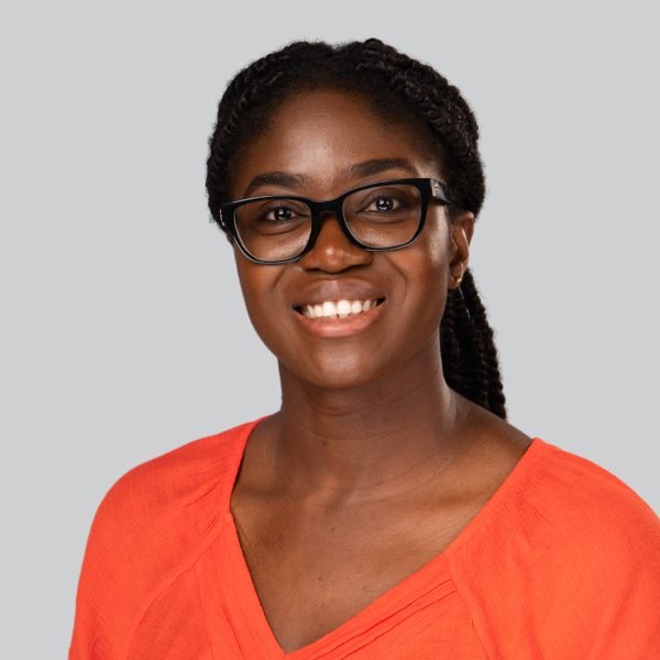 Event headshot booth portrait of a woman in glasses and a coral v-neck top