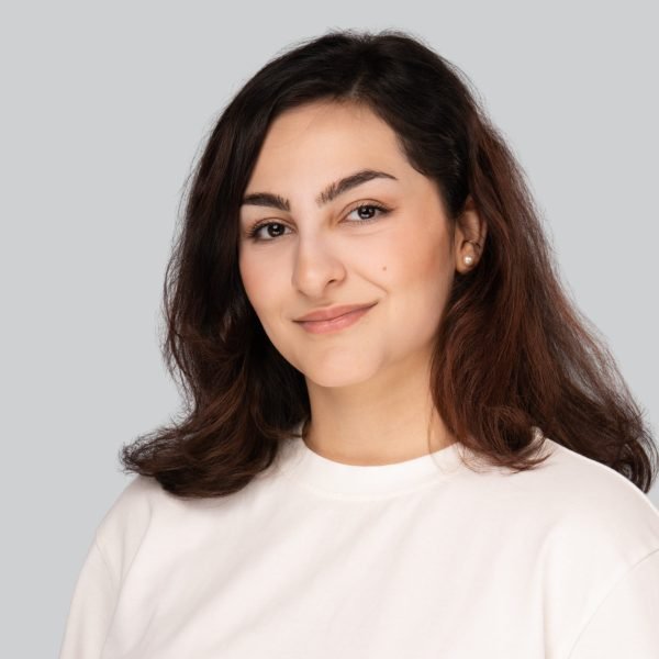Event headshot of a woman with long dark hair in a white top on a grey backdrop
