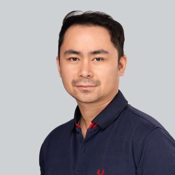 Event headshot of a man in a navy polo shirt on a grey studio backdrop