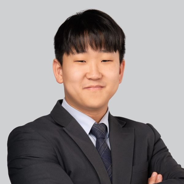Event headshot of a young man in a navy suit and tie, arms crossed