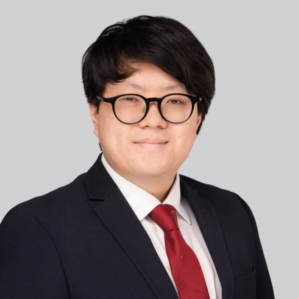 Event headshot of a person in a navy suit and red tie on a grey studio backdrop