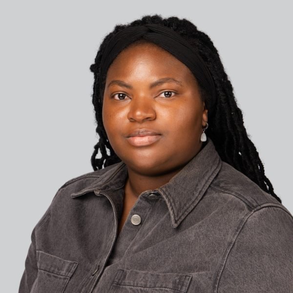 Event headshot of a woman with long braids in a grey utility shirt