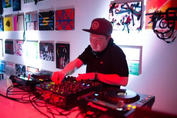 DJ playing a set under red lighting at a late night gallery event in Vancouver