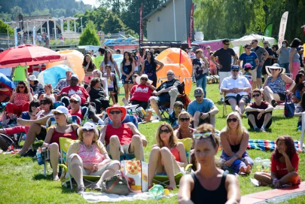 Festival audience seated on the lawn under umbrellas watching the main stage