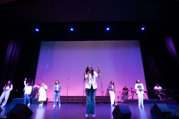 Wide concert photograph of a full band performing under stage lighting in a Vancouver theatre
