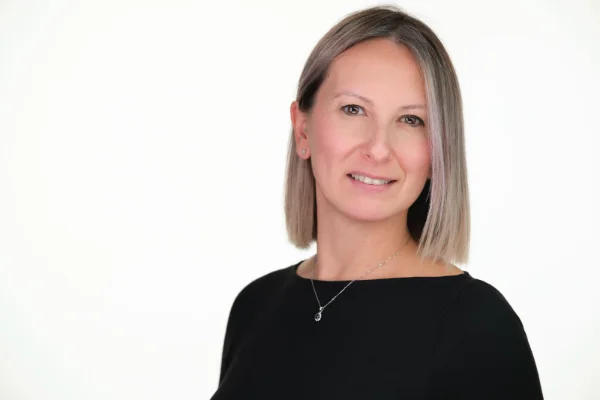 Professional headshot of a woman in a black top photographed on a white studio backdrop